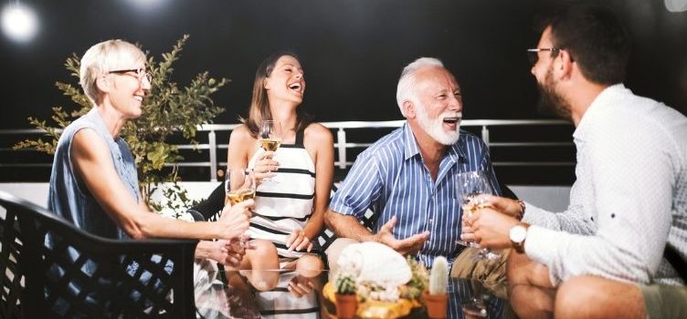 senior couple and friends laughing over dinner