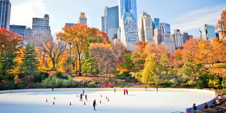 View of ice skaters in central park with the New York skyline as a backdrop