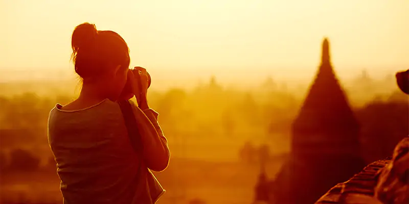 a woman taking a photo of a city skyline at sunset