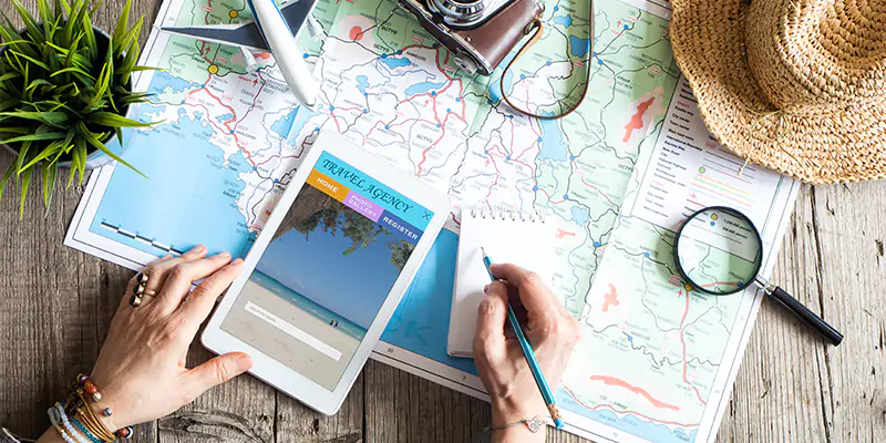a person writing notes with a map and magnifying glass