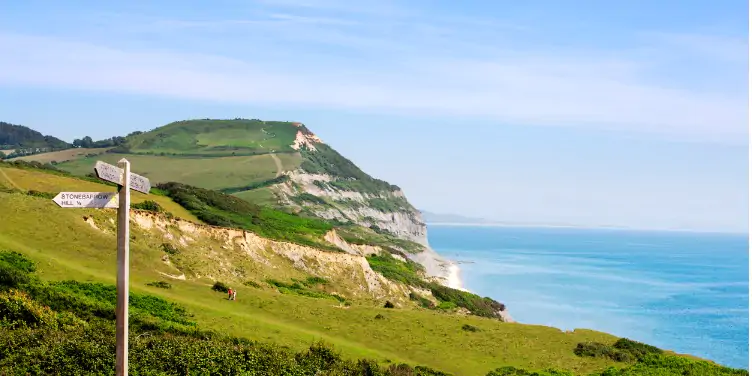 an image of a signpost on a Jurassic Coast walking trail, with the Golden Cap in the background