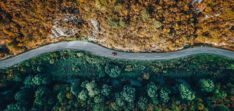 A car drives on a gravel road with the stunning Vestrahorn Mountain as the backdrop during an Icelandic sunset, highlighting the possibility of renting a car in Europe for an unforgettable journey.