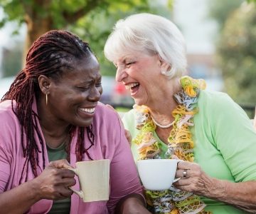 two senior female friends laughing over coffee