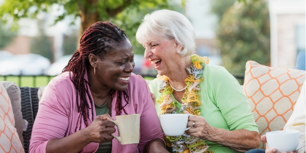 two senior female friends laughing over coffee