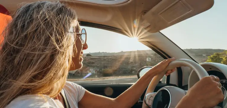 Sunny view and close up picture of a woman driving a rental car around Europe.