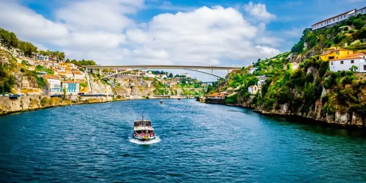 A boat full of tourists on the Douro river in Porto during a sunny day of summer