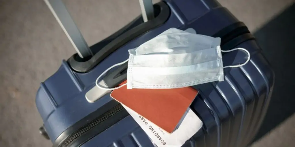 Suitcase with medical mask and boarding pass