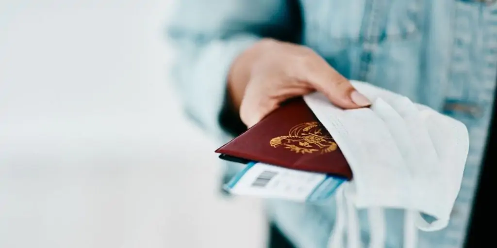 Woman holding passport and face mask