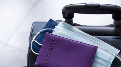 suitcase with facemask and passport covid