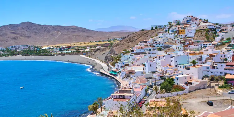 an image of Las Playitas, Fuerteventura with multicolour houses staggered up a hill on the coast