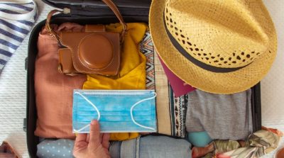 an image of someone packing a face mask into their suitcase when preparing to go on holiday