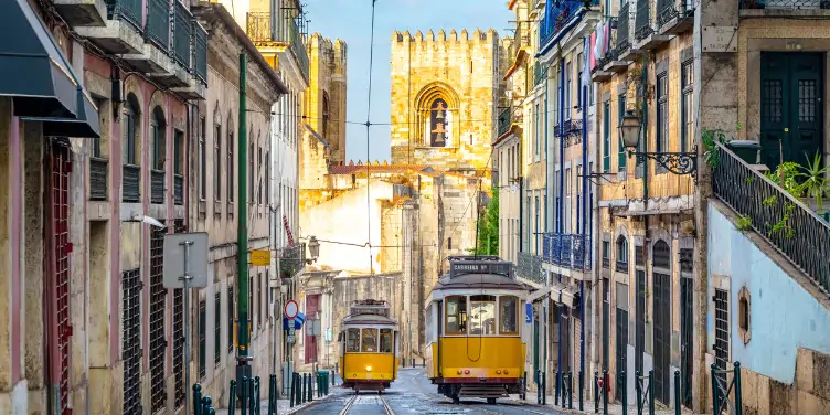  Traditional Portuguese yellow trams passing through narrow streets of the city centre.