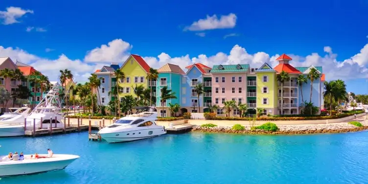 colourful houses on a small harbourfront with turquoise water and small yachts in Nassau, Bahamas