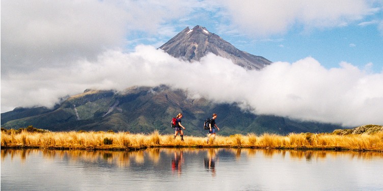 an image of hikers in front of Mount Taranaki, New Zealand
