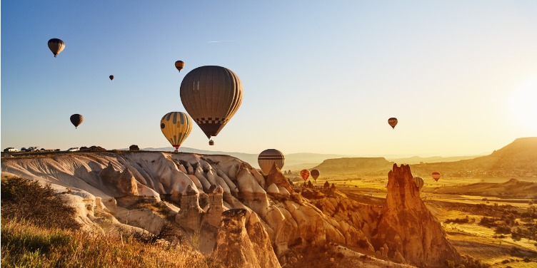 an image of hot air balloons flying over Cappadocia, Turkey at sunset