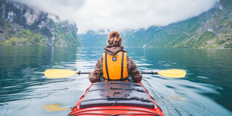 an image of a woman kayaking in a Norwegian fjord