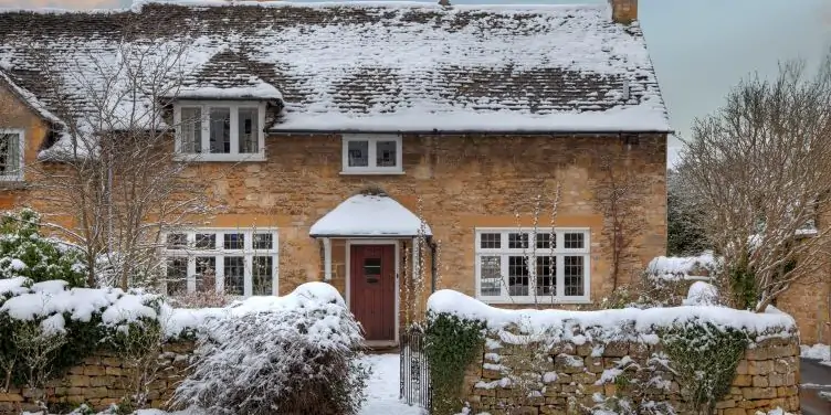 Pretty Cotswold cottage in snow in Worcestershire, England.