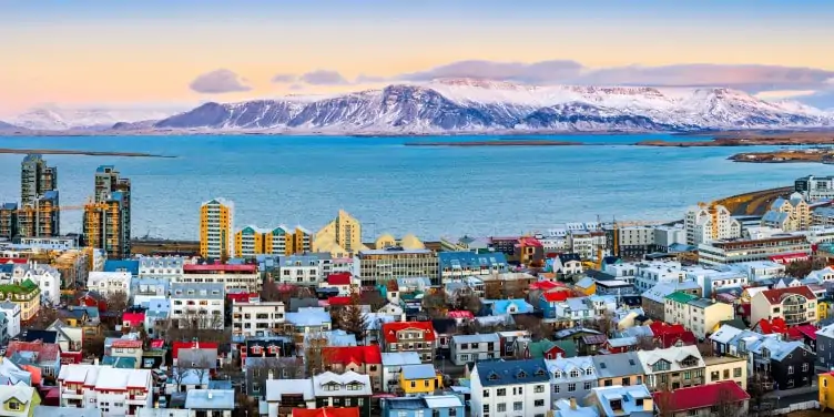 View of Reykjavik and its colourful houses at sunset with snowy mountains in the background