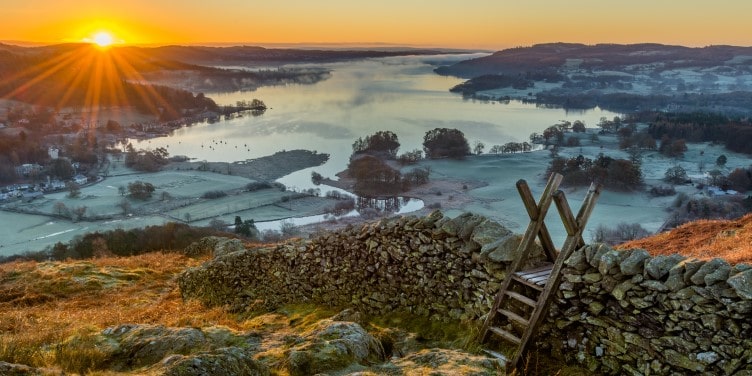 Stone wall with a sunrise over Lake Windermere in the background