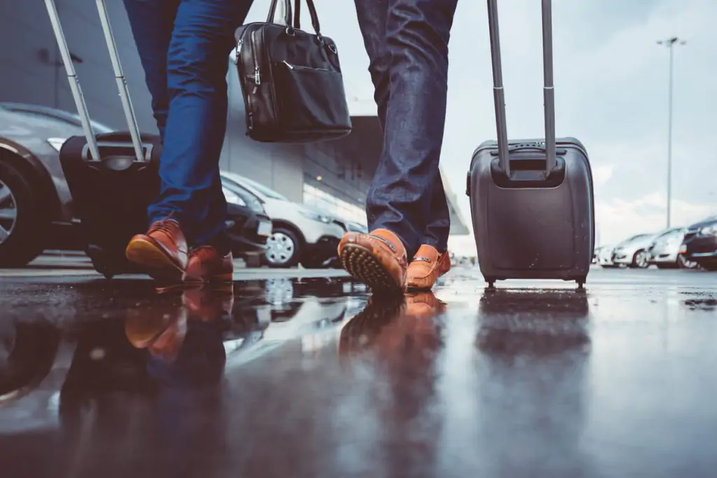 Two people walking with pull along suitcase in airport car park