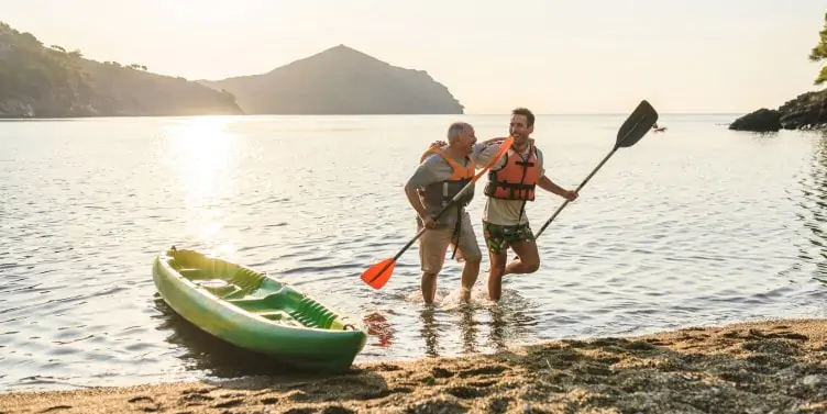 Male kayakers walking on the beach