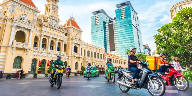 Motorcyclists make their way through the city in front of the Saigon City Hall in Ho Chi Minh city