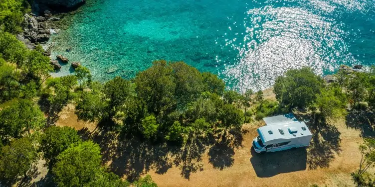 Camper van parked up on the coast next to a rocky beach on a summer's day