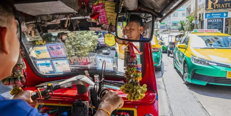 Tuk tuk driver in navigating rush hour traffic