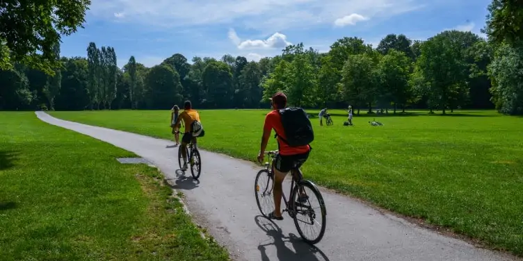 Two cyclists cycling through Munich’s bike-friendly public park, Englischer Garten.