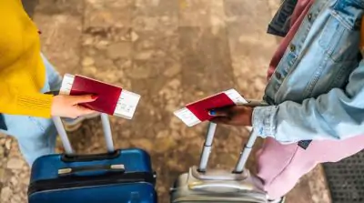 an image of two women holding passports with their suitcases