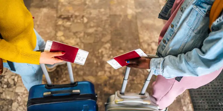 an image of two women holding passports with their suitcases