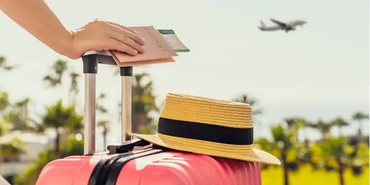 an image of a woman holding a passport with a pink suitcase and straw hat