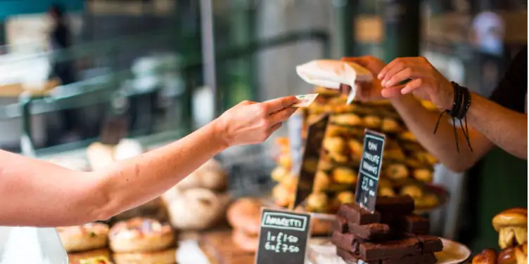 an image of a tourist paying for a sweet pastry with cash at a market