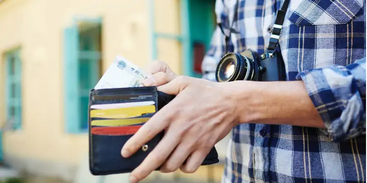 an image of a man holding his wallet with credit/debit cards and travel money inside
