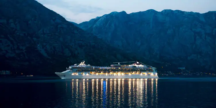 A cruise ship at night in front of mountains