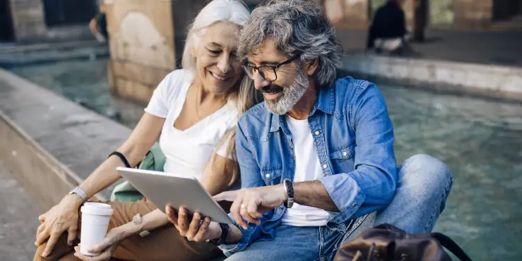 Mature couple sat down in Barcelona, using a tablet.