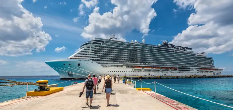 Groups of people walking onto their holiday cruise with luggage.