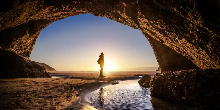 Man travelling in off-season on an empty beach standing by a beautiful cove.