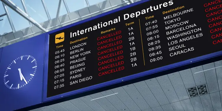 An airport screen showing flight statuses, most of them cancelled.