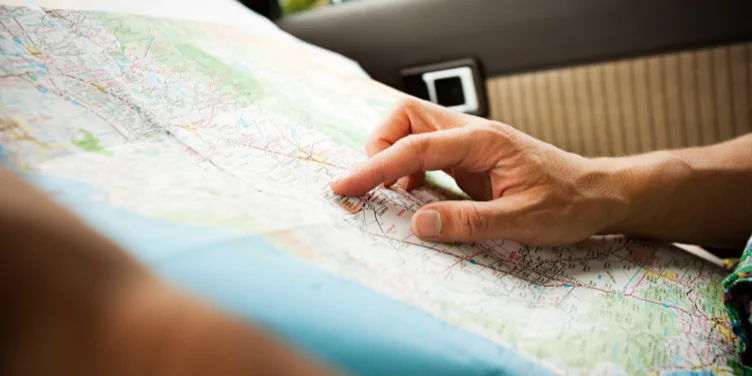 Someone sat in a car holding a map, navigating their way on their independently booked road trip