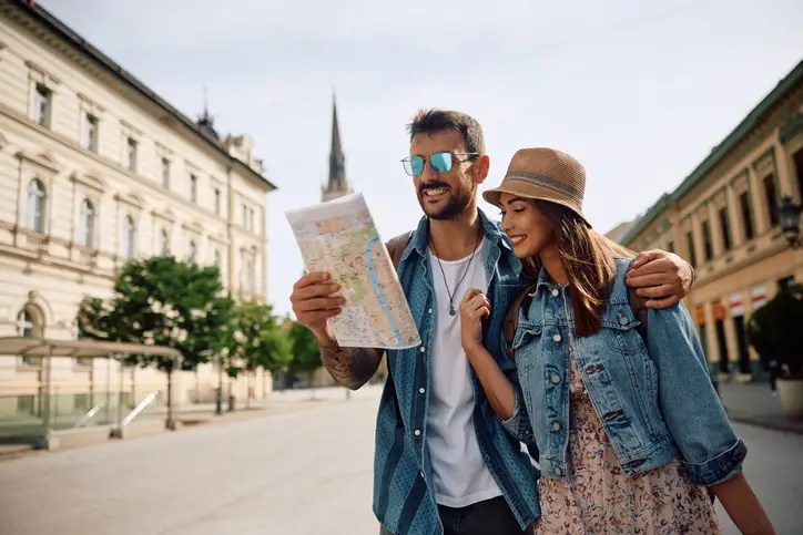 Happy couple of tourists reading map while walking through the city. Copy space.