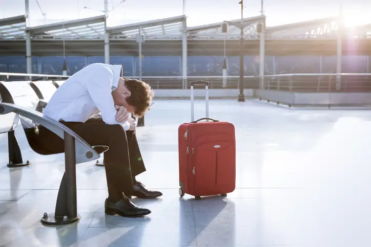 Depressed traveler waiting at airport, flights delays and cancellations