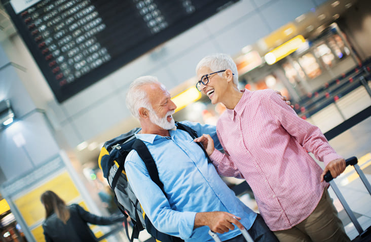 happy older couple planning to travel inside an airport