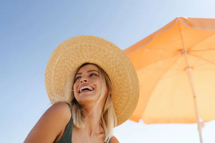 an image of a girl wearing a hat under a shade in a beach