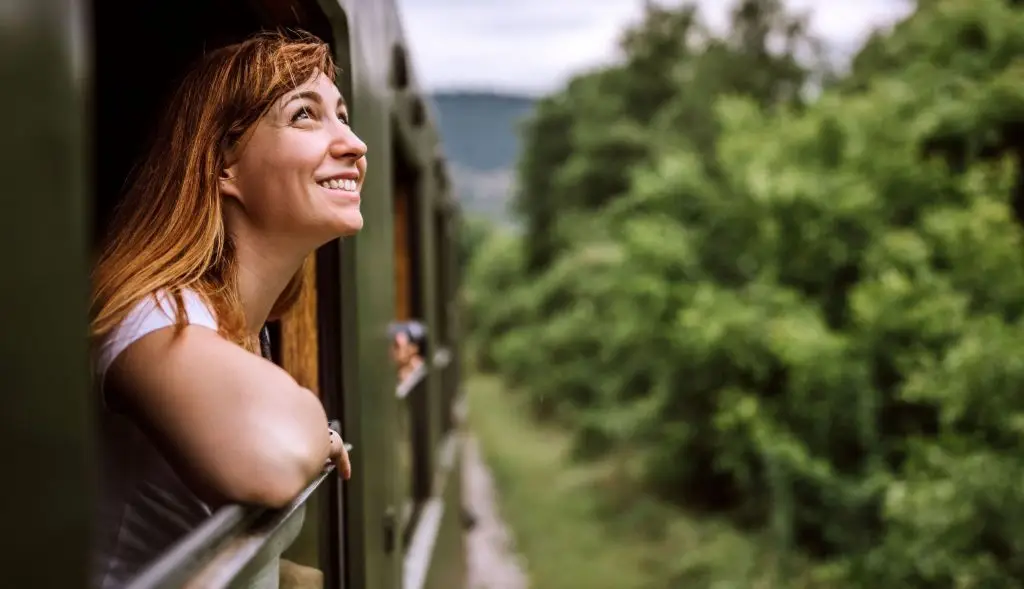 A woman looking out the window and enjoying the scenic view during a train journey